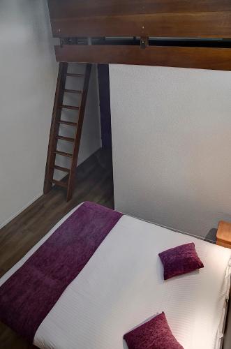 a bed with purple pillows on it with a ladder at Logis Le Relais de Sassenage in Sassenage