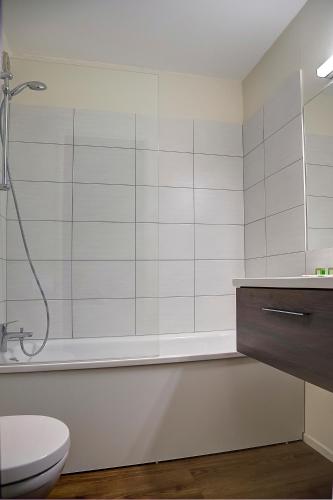 a white bathroom with a shower and a toilet at Logis Le Relais de Sassenage in Sassenage