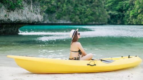 a woman sitting in a yellow kayak on a beach at Sea Passion Hotel in Koror