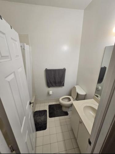 a white bathroom with a toilet and a sink at Miami Stay - Pool, Parking, & Affordable Transportation in Tamiami