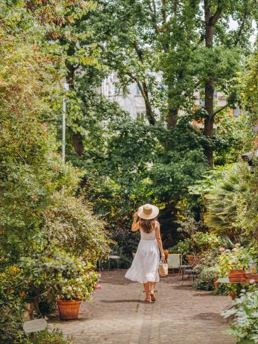 a woman in a white dress and hat walking through a garden at Hotel des Grandes Ecoles in Paris