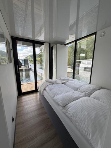 a large bed in a room with large windows at Design-Hausboot am Rheinsteig in Lorch am Rhein