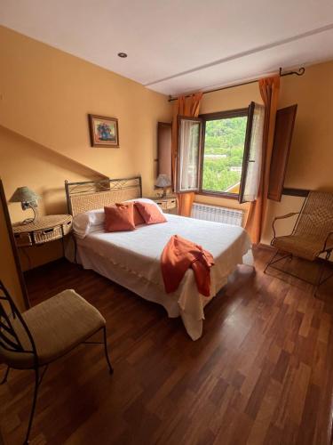 a bedroom with a bed and a window and a chair at Apartamentos La Guergola in Pola de Somiedo