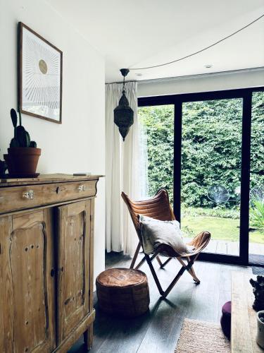 a room with a chair and a dresser and a window at Prive rustplek op de Veluwe met jacuzzi in Ermelo