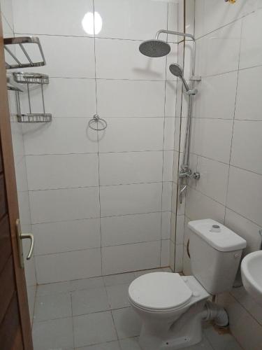 a white bathroom with a toilet and a sink at L'hospitalité in Thies