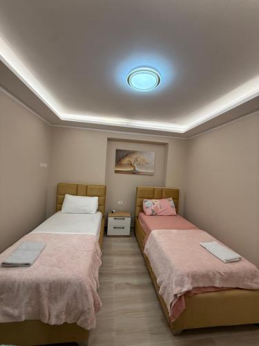 a room with two beds and a light on the ceiling at Alea Home in Fier