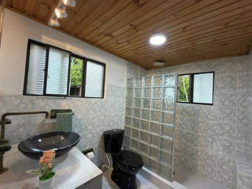 a bathroom with a sink and a toilet and windows at Vereda San Jorge Chalet in Zipaquirá