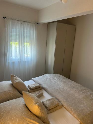 a bedroom with two beds with pillows and a window at Apartman LaVida in Kaštela