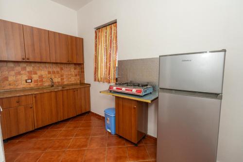 a kitchen with a stainless steel refrigerator and wooden cabinets at Vila Pushimi Klaudio in Velipojë