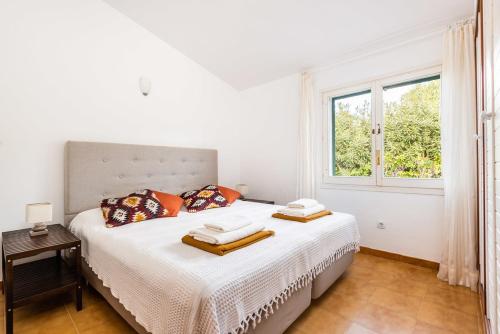 a white bedroom with a bed with pillows and a window at Estrella Del Mar with Private Pool in Binibeca