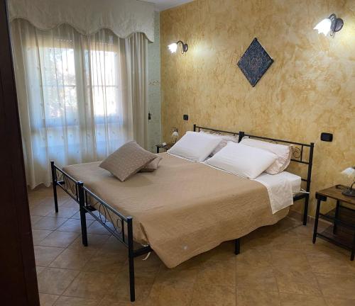a bedroom with a bed with white pillows and a window at Domu Bella in Decimomannu
