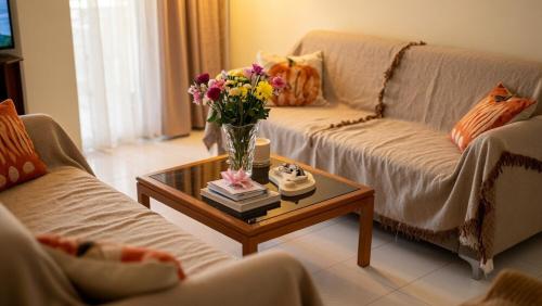 a living room with a vase of flowers on a coffee table at Kalamata Deluxe Suite By AGGELOS in Kalamata