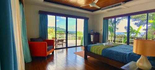 a bedroom with a bed and a chair and a balcony at Unique panoramic sea view pool villas in Phuket