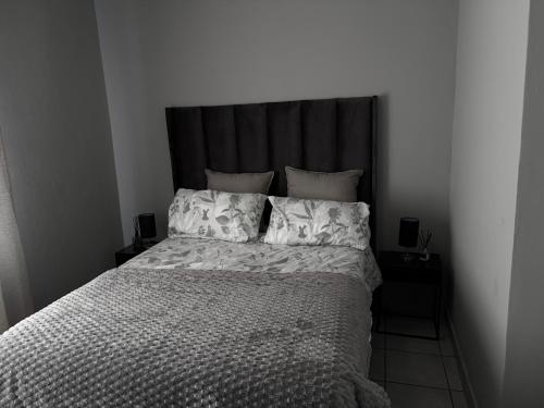 a bedroom with a large bed with a black headboard at Zoe in Centurion