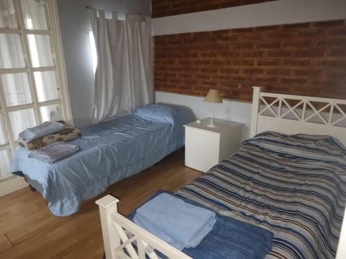 a bedroom with two beds and a brick wall at Lo de Norma in Neuquén