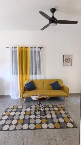 a living room with a yellow couch and a rug at Le Mäysa dzindzano Residence in Sada