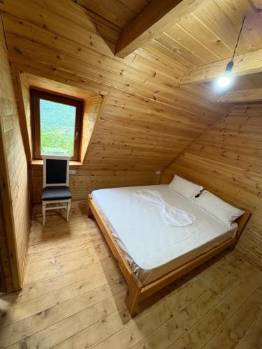 a bedroom with a bed and a chair in a wooden room at Nini Guesthouse Theth in Theth