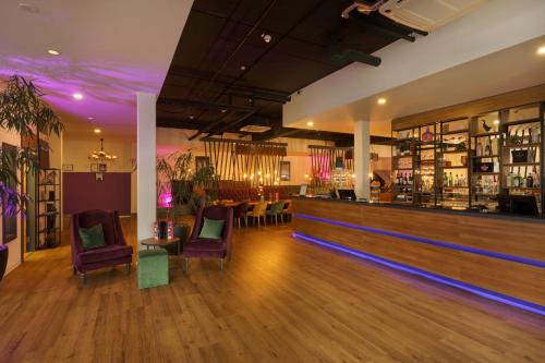 a bar with purple lighting and chairs in a room at DIWOTEL by Trip Inn Frankfurt Airport Dreieich in Dreieich