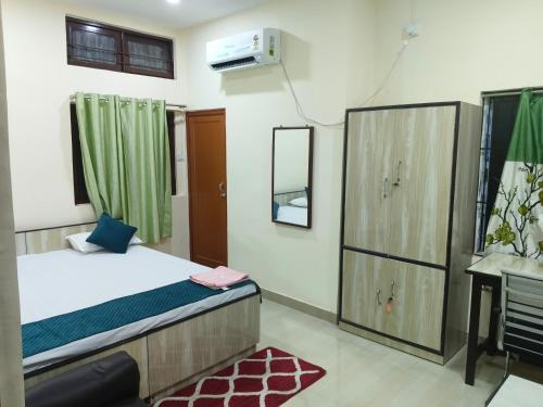 a small bedroom with a bed and a mirror at Basudev Lodge in Dibrugarh