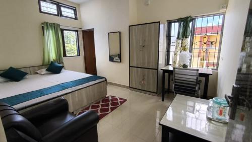 a bedroom with a bed and a desk and window at Basudev Lodge in Dibrugarh
