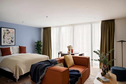 a bedroom with a bed and a couch and a chair at Cove Landmark Pinnacle in London