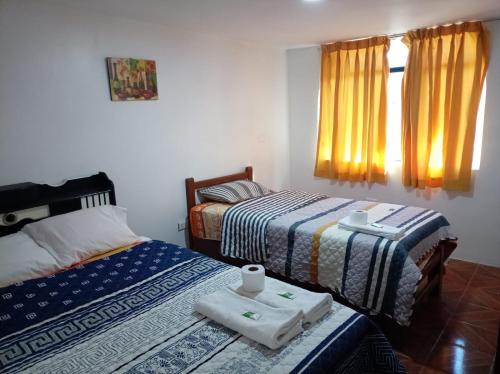a bedroom with two beds with towels and a window at Nery Lodging in Huaraz