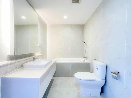 a white bathroom with a toilet and a sink at The Astra Residence in Chiang Mai