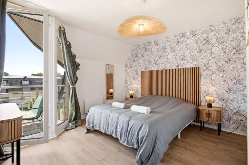 a bedroom with a bed and a balcony at Le Calmette - Balcon, Parking & Ascenseur in Caen