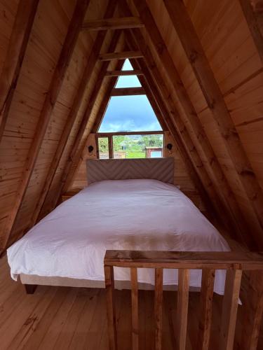 a bed in a wooden room with a window at Monte Waïa in Guasca
