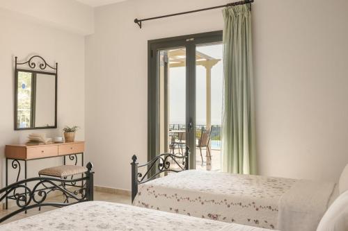 a bedroom with two beds and a desk and a window at Villa Dora in Kefallonia