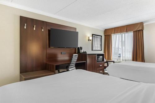 a hotel room with two beds and a desk and a television at Best Western Plus Dryden Hotel and Conference Centre in Dryden