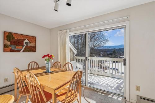a dining room with a table and chairs and a large window at Mountainside Condo J202 in Stowe