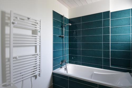 a bathroom with a tub and green tiles at L'Épine - Maison lumineuse - 300m de la plage in LʼÉpine