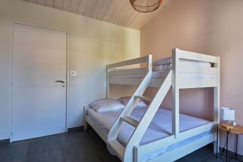 a bunk bed room with two bunk beds and a door at L'Épine - Maison lumineuse - 300m de la plage in LʼÉpine