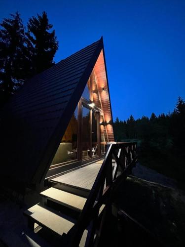 a small house with a wooden deck at night at A-Frame Tadić Tara in Ljuboš