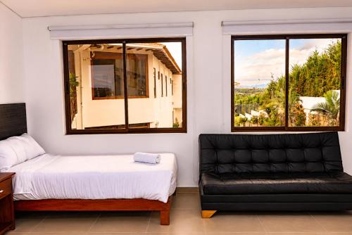 a bedroom with a bed and a couch and two windows at Hotel PUENTE PIEDRA PARK in Villa de Leyva