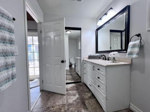 a white bathroom with a sink and a mirror at Anaheim California, Beautiful Pool Home, Short Walk to Disney in Anaheim