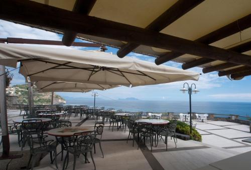 an outdoor patio with tables and chairs and umbrellas at Hotel Loreley in Ischia