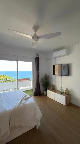 a white bedroom with a bed and a flat screen tv at LĀ KAI - Piso Carabelas in Candelaria