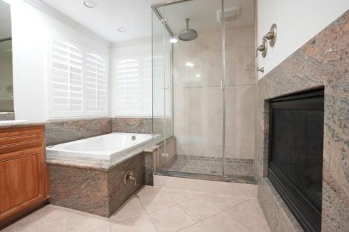 a bathroom with a tub and a shower and a fireplace at Amazing Large Family Home w/Pool, 1 Mile to Disney in Anaheim