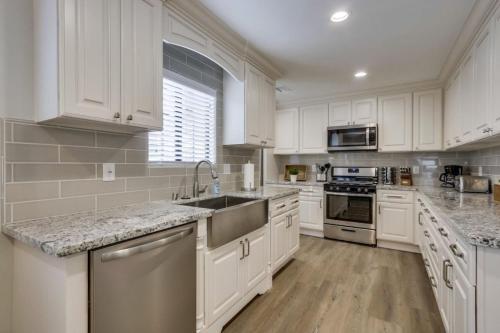 a white kitchen with white cabinets and a sink at 5 Bedroom plus loft room, 3 Bath home in Fullerton