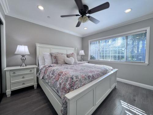 a bedroom with a bed with a ceiling fan and a window at Stunning 8 bedroom 6 bathroom Pool Home in Anaheim