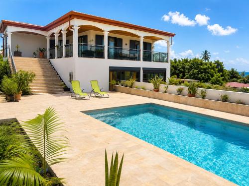 a villa with a swimming pool in front of a house at L'Escapade Volcanique in Sainte-Rose