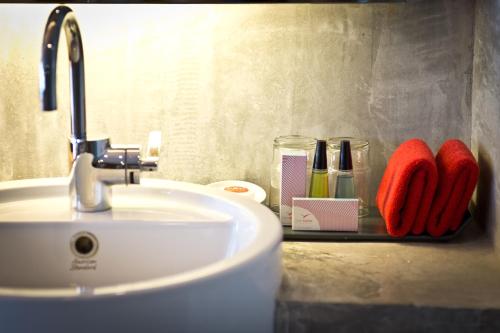 a bathroom sink with red mittens on a counter at The Now Hotel - SHA Extra Plus in Jomtien Beach