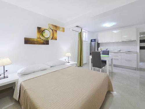 a bedroom with a bed and a desk and a kitchen at House Gorica 2 - underground level apartments in Baška