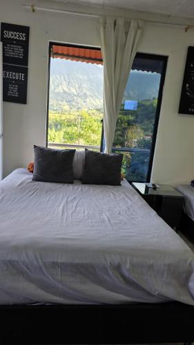 a bedroom with a large bed with a large window at CASA HOTEL COCORNa in Cocorná