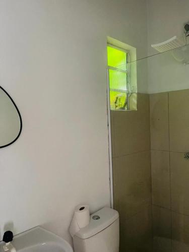 a white bathroom with a toilet and a shower at Pousada Coral in Osório