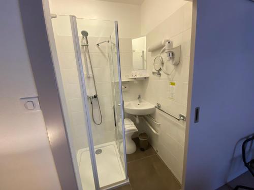 a bathroom with a glass shower and a sink at Hotel de Montaulbain in Verdun-sur-Meuse