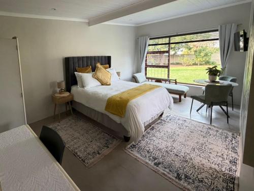 a bedroom with a bed and a desk and a window at McCrae's Garden Suite in Malmesbury
