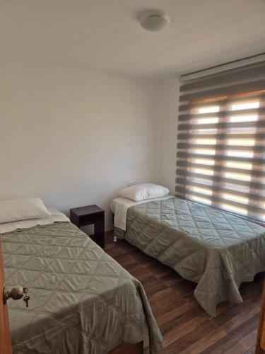 a bedroom with two beds and a window with blinds at Los Olivos del Colibri in Tambillos